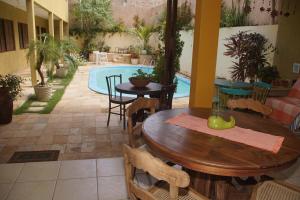 une terrasse avec une table, des chaises et une piscine dans l'établissement Hospedaria Lua Raio de Sol, à Natal