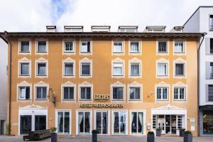a large orange building with white windows at Garner Hotel Friedrichshafen by IHG in Friedrichshafen
