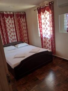a bedroom with a large bed with red curtains at Cabana Coral Reef in Mandapam