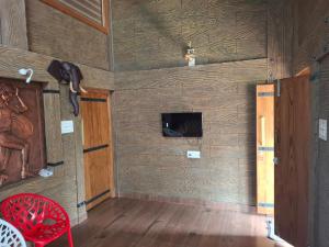 a room with a wooden wall with a tv and a red chair at Mountain Meadows Resort in Kollengode +21 photos