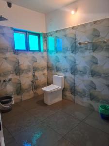 a bathroom with a toilet and a wall with blue lights at Mountain Meadows Resort in Kollengode