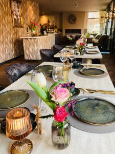 a table with plates and a vase with flowers on it at De La Frontière Bed & Borrelbistro in Slenaken