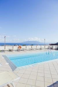 a swimming pool with chairs and the ocean in the background at Grand Hotel Cesare Augusto in Sorrento