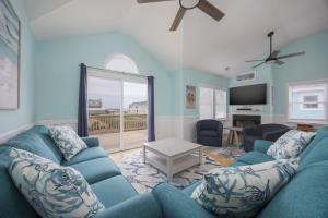 a living room with a blue couch and a tv at 5319 - Day Dreamz in Kill Devil Hills
