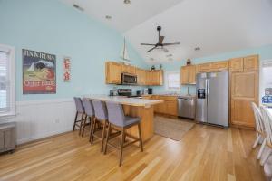 a kitchen with wooden cabinets and a kitchen island with chairs at 5319 - Day Dreamz in Kill Devil Hills +42 photos