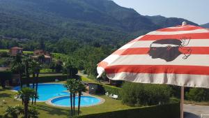 an umbrella next to a swimming pool with a mountain at La terrazza sul Lago Maggiore in Brezzo
