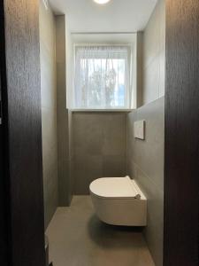 a small bathroom with a toilet and a window at Apartmán Bytča in Bytca +2 photos