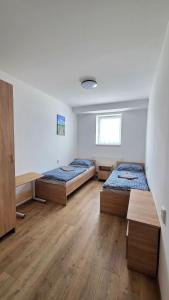 two beds in a room with wooden floors at Apartmán Bytča in Bytca