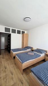 three beds in a room with wooden floors at Apartmán Bytča in Bytca