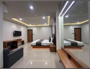 a bedroom with two beds and a couch and a television at Hotel Peacock Anand in Anand +11 photos