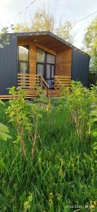a small house with a deck in a field of grass at Han Karakol in Karakol +19 photos