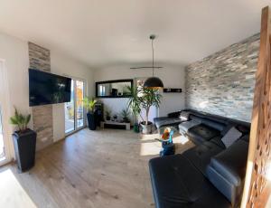 a living room with a black couch and a brick wall at Spa-Villa mit privatem Whirlpool&Sauna und Panoramablick in Wellheim
