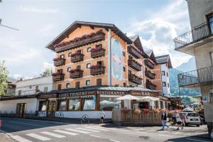 a building on a street with people walking in front of it at Hotel Primiero in Tonadico