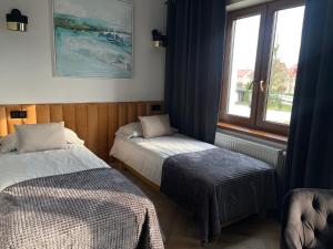 a room with two beds and a window at Hotel & Restauracja Kormoran in Orzysz