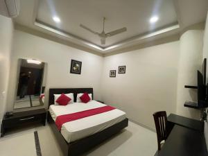 a bedroom with a bed with red pillows and a television at Hotel Oval Hut in Jalandhar +1 photo