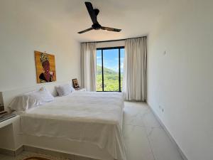 a white bedroom with a bed and a ceiling fan at Villa Blanca only accessible by 4x4 vehicle in El Valle +7 photos