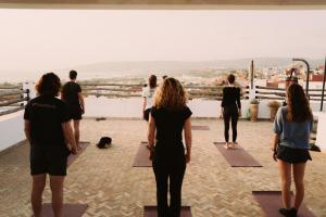 a group of people doing yoga on the roof of a building at Surf and Friends in Tamraght Ou Fella
