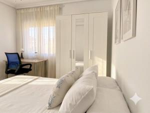 a bedroom with a bed with white sheets and pillows at Apartamento EL SOL DEL ZAPILLO in Almería