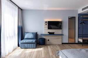 a living room with a chair and a television at Holiday Inn - the niu, Quay Hamburg Harburg by IHG in Hamburg