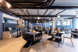 a restaurant with tables and chairs and a bar at Holiday Inn - the niu, Quay Hamburg Harburg by IHG in Hamburg