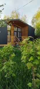 a small wooden house with a deck in a yard at Han Karakol in Karakol