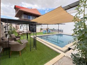 ein Haus mit einem Swimmingpool mit einem großen Sonnenschirm in der Unterkunft panorama villa boutique HT in Jericho
