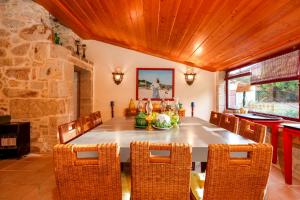a dining room with a table and chairs and a stone wall at Casa Justininho in Ponte de Lima
