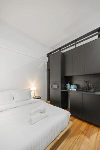 a bedroom with a large white bed and a kitchen at South Beach Studio - Simple Base, Walk Everywhere in South Fremantle