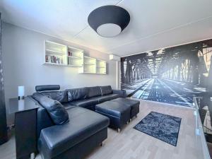 a living room with a black leather couch and stool at Moderni kolmio Ilmainen Pysäköinti! in Jyväskylä