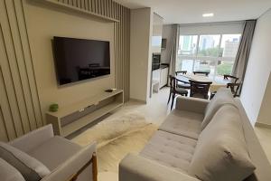 a living room with a couch and a tv and a table at Edificio Elegance in Foz do Iguaçu