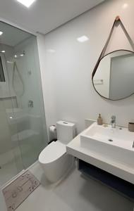 a bathroom with a toilet and a sink and a mirror at Edificio Elegance in Foz do Iguaçu