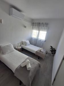 a bedroom with two beds and a couch and a window at Casa R in Sesimbra