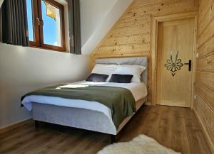 a bedroom with a bed with a wooden wall at Apartamenty Klikuszówka in Nowy Targ