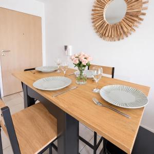 a dining room table with plates and a vase of flowers at T2 moderne avec terrasse, central et calme in Saint-Herblain