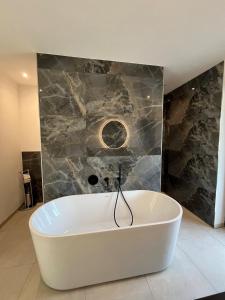 a white bath tub in a room with a stone wall at Design-Villa mit privatem Whirlpool&Naturblick in Wellheim