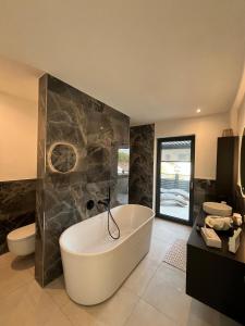 a large bathroom with a tub and a toilet and a sink at Design-Villa mit privatem Whirlpool&Naturblick in Wellheim