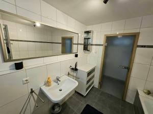 a white bathroom with a sink and a mirror at RUWERA SONNENHÜGEL - Moderne Ferienwohnung - eigener Eingang, Garten und Terrasse in Trier +17 photos