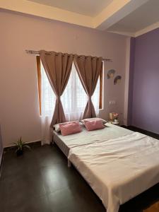 a bedroom with a large bed with pink pillows at inoru house in Khairāni