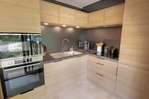 a kitchen with wooden cabinets and a sink at Chalet HABIA TXIKIA 4 pers, neuf, sur Hasparren, calme, avec piscine et climatisation, Pays Basque in Hasparren