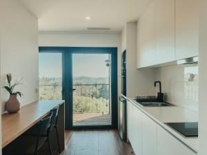 a kitchen with white cabinets and a large window at Bungalows da Travanca in Arcos de Valdevez
