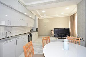 a white kitchen with a white table and chairs at Elite & Grand Luxury Hotel Apartments in Central Yerevan, By Opera and Northern Avenue in Yerevan +9 photos