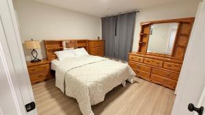 a bedroom with a bed and a dresser and a mirror at Befitting Crown Suite in Moncton