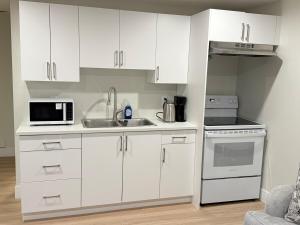 a kitchen with white cabinets and a sink and a microwave at Befitting Crown Suite in Moncton