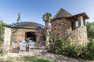 a stone house with a table and chairs outside at Holiday House La Teja in Facinas