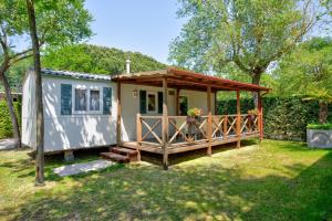 a tiny house with a porch in a yard at Camping Klaus in Cavallino-Treporti