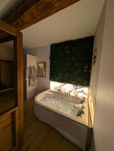 a large bath tub in a room with ivy on the wall at Suite avec jacuzzi privatif in Vergèze