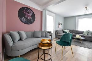 a living room with a gray couch and a pink wall at The Smith - Renovated 4 Bedroom in Bloomfield