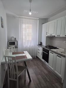 a kitchen with white cabinets and a table and chairs at Wonderful Apartment in Braşov