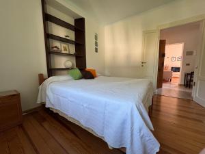 a bedroom with a white bed and a wooden floor at Limonta, Fiori e Lago Private Apartment in Limonta