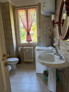 a bathroom with a sink and a toilet and a window at Limonta, Fiori e Lago Private Apartment in Limonta +33 photos